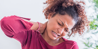 A woman holds her neck in pain from Cervical Degenerative Disc Disease