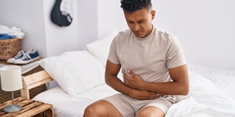A young man holds his stomach in pain due to norovirus