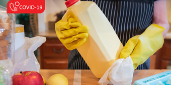 Individual wearing latex gloves, cleaning groceries