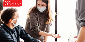 Office workers wearing a mask, collaborating in a post-COVID-19 work environment