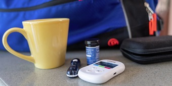 Coffee cup, blood sugar testing kit for diabetes, sitting on a counter top