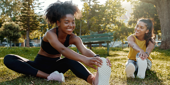 Two 20-something females stretching in a park
